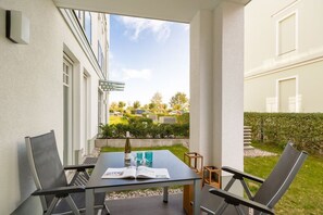 Ein Balkon mit Tisch, Stühlen und einer Weinflasche.