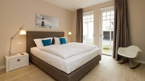 Une chambre à coucher avec un lit, des lampes de chevet, une chaise, un tableau et une vue par la fenêtre.