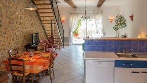 A dining area with a checkered tablecloth, wooden chairs, and a staircase leading to an upper level. - Holiday Home in Murviel with French Garden (Murviel-Les-Beziers)
