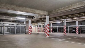 Un estacionamiento subterráneo con pilares de hormigón, puertas de garaje abiertas y un coche dentro.