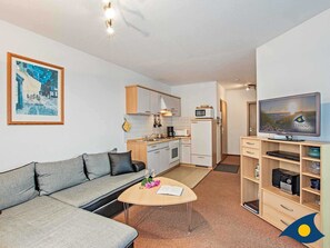 Un appartement moderne comprenant un espace de vie, une kitchenette et un téléviseur.
