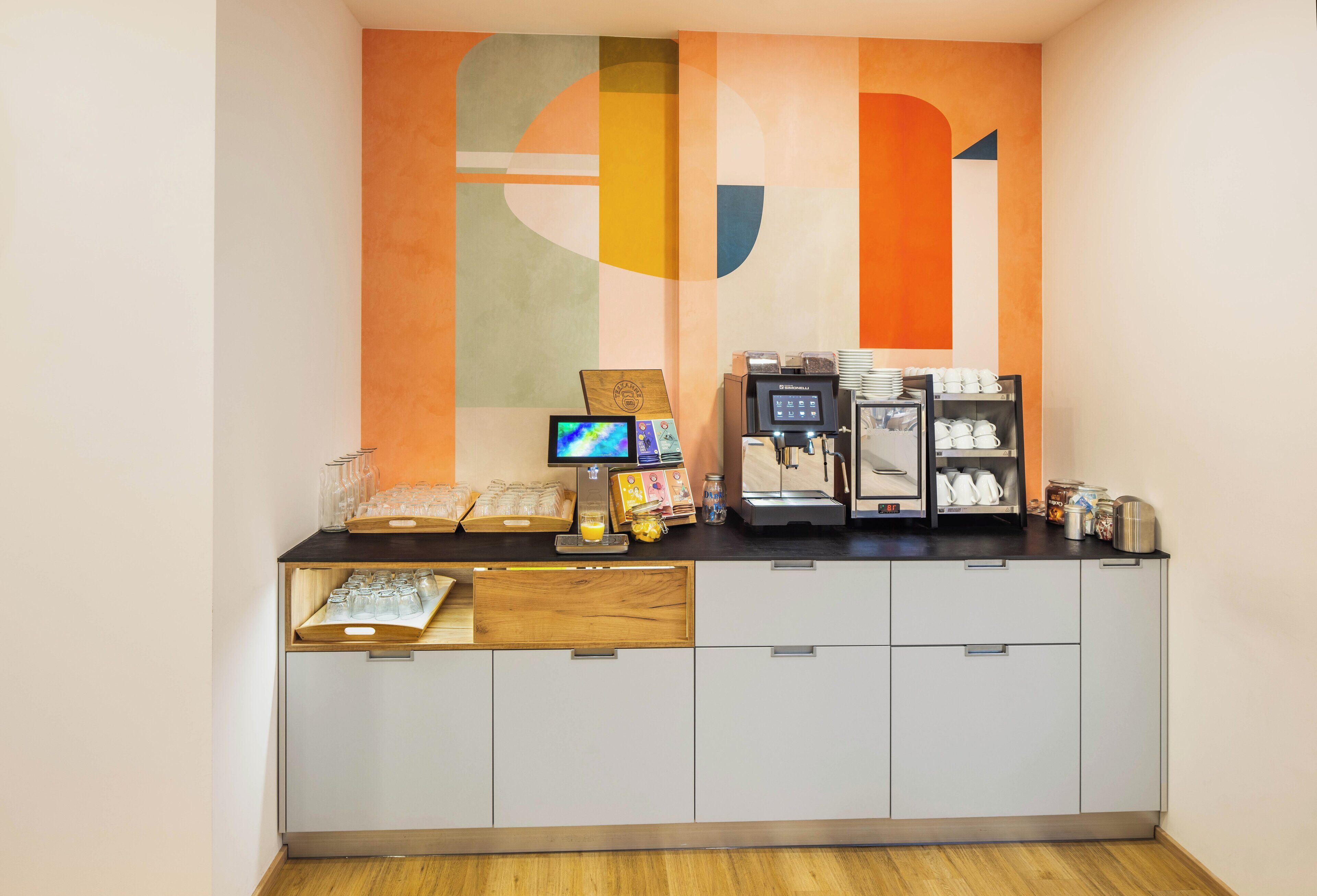 Un espace dédié au café, équipé d’un écran numérique, d’une machine à café, ainsi que de différents types de tasses et de récipients à café.