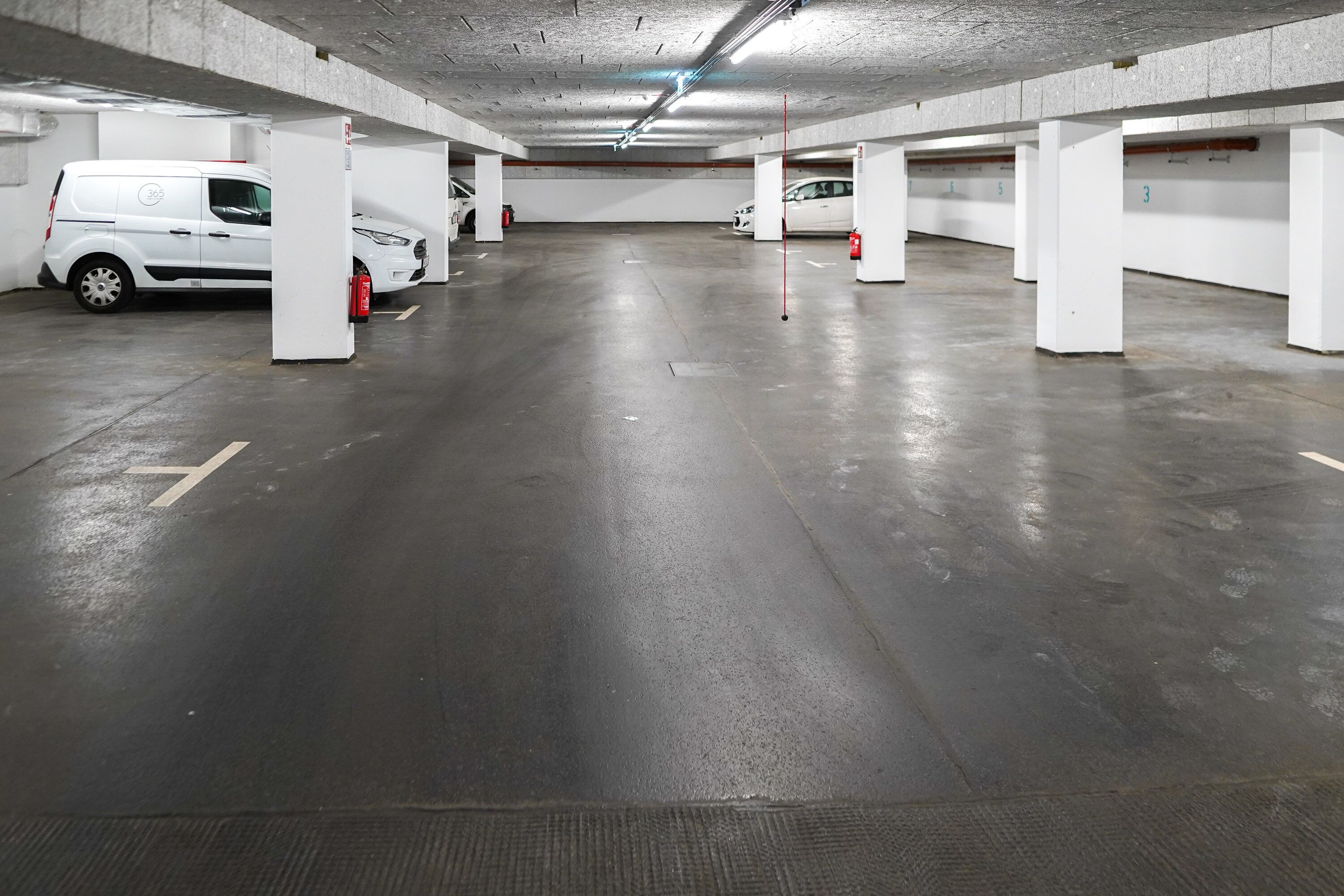 Eine mehrgeschossige Parkgarage mit weißen Säulen und einem sauberen, polierten Boden.
