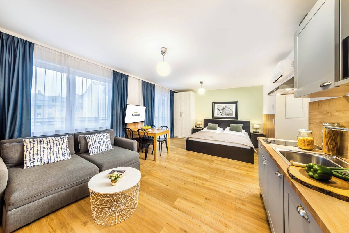 A modern hotel room with a sofa, dining table, and a bed.
