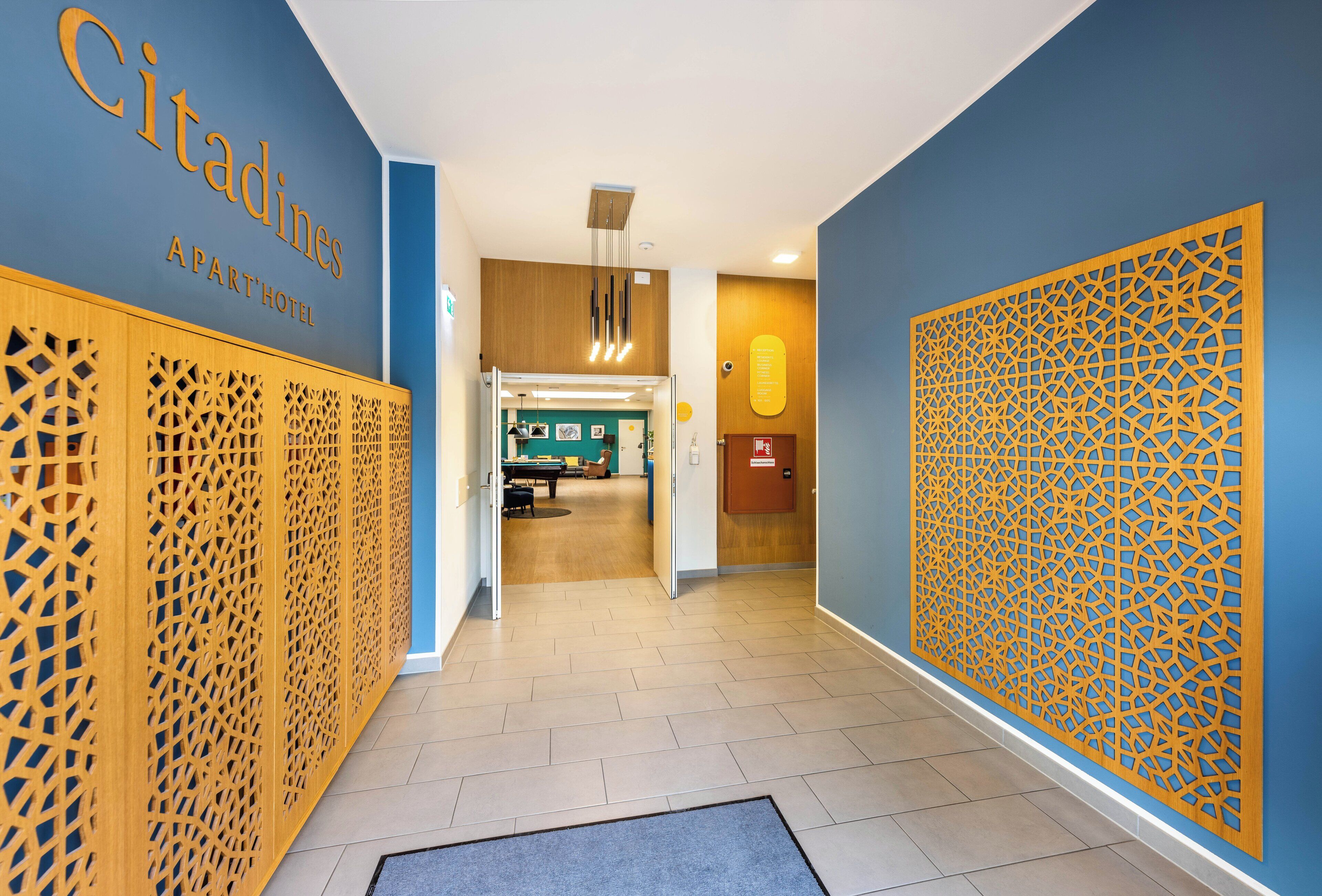 Un corridoio con una parete blu, un pannello decorativo in legno e una porta che dà su una stanza con il biliardo.