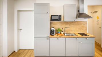 A compact kitchen with a microwave, coffee maker, and sink.