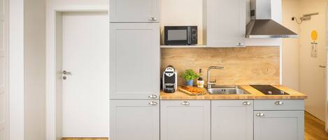 Cocina compacta con microondas, cafetera y lavamanos.