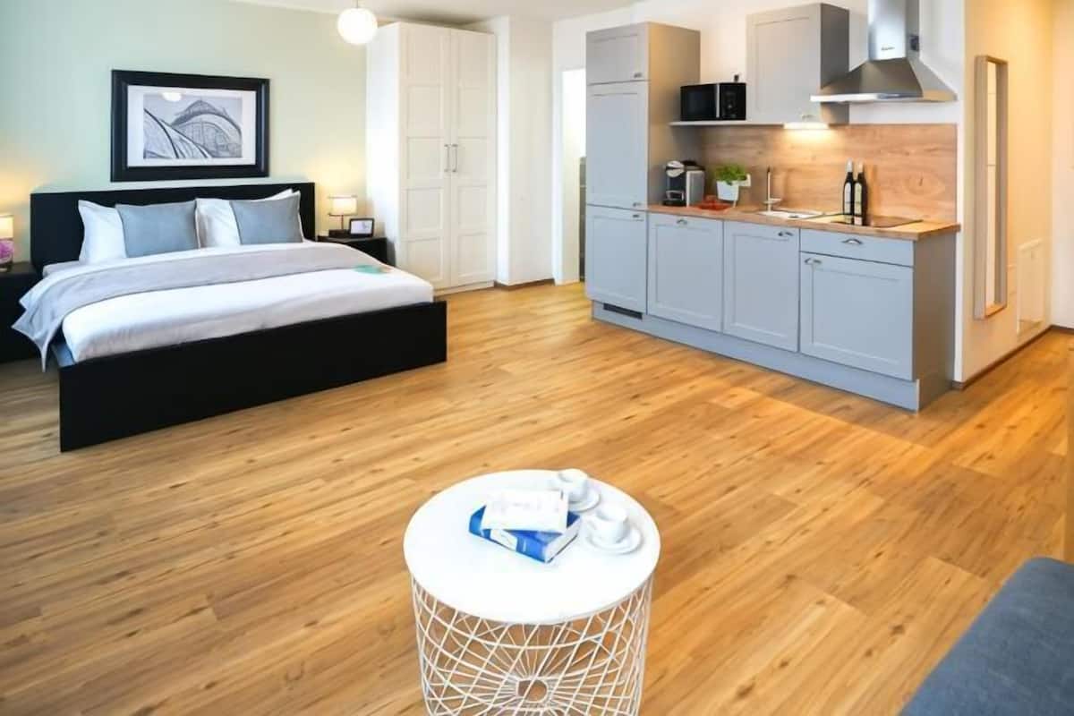 A modern bedroom with a bed, bedside table, and a round white table with a towel.