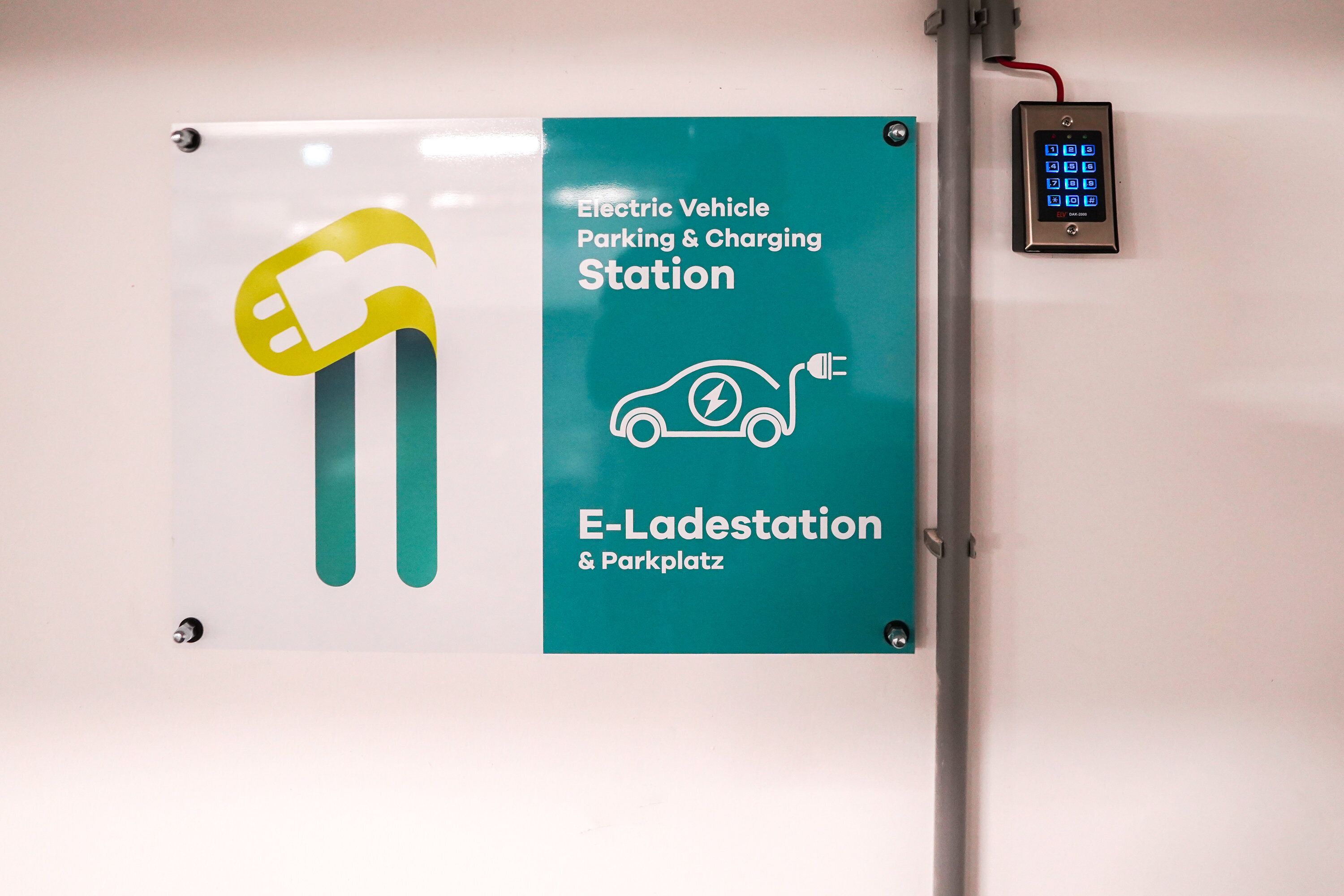 En skylt som visar var man kan parkera och ladda en elbil, med en digital knappsats.