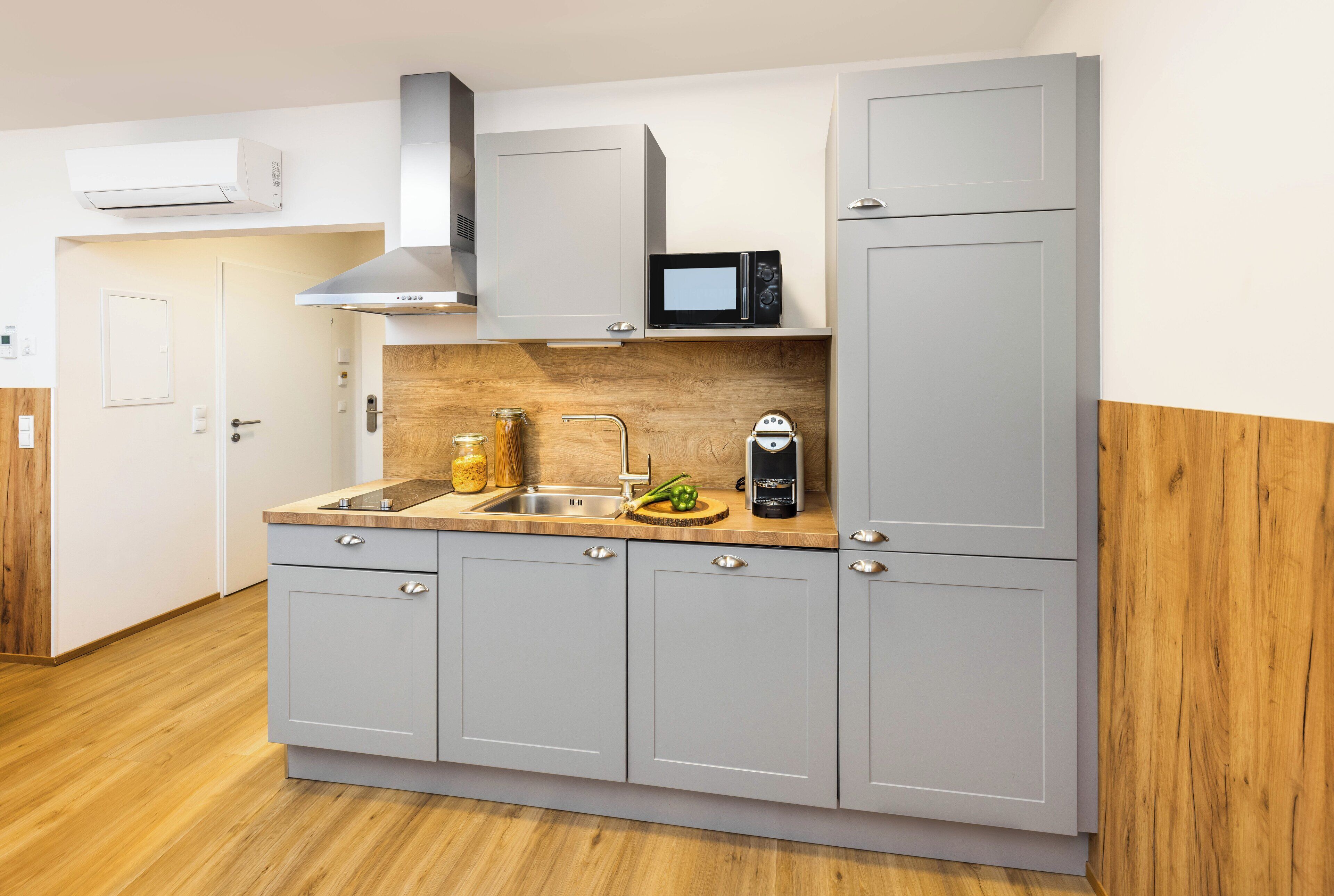 A modern kitchen with grey cabinets, a microwave, and a sink.