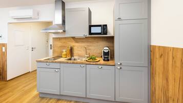A modern kitchen with grey cabinets, a microwave, and a sink.