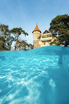 A clear view of a swimming pool with a tower and building in the background. - Zamek Leba (Leba)