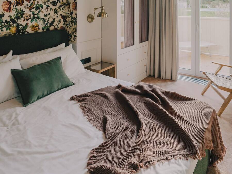 Un dormitorio con cama, lámpara colgante, armario y vista al exterior a través de una puerta de cristal.