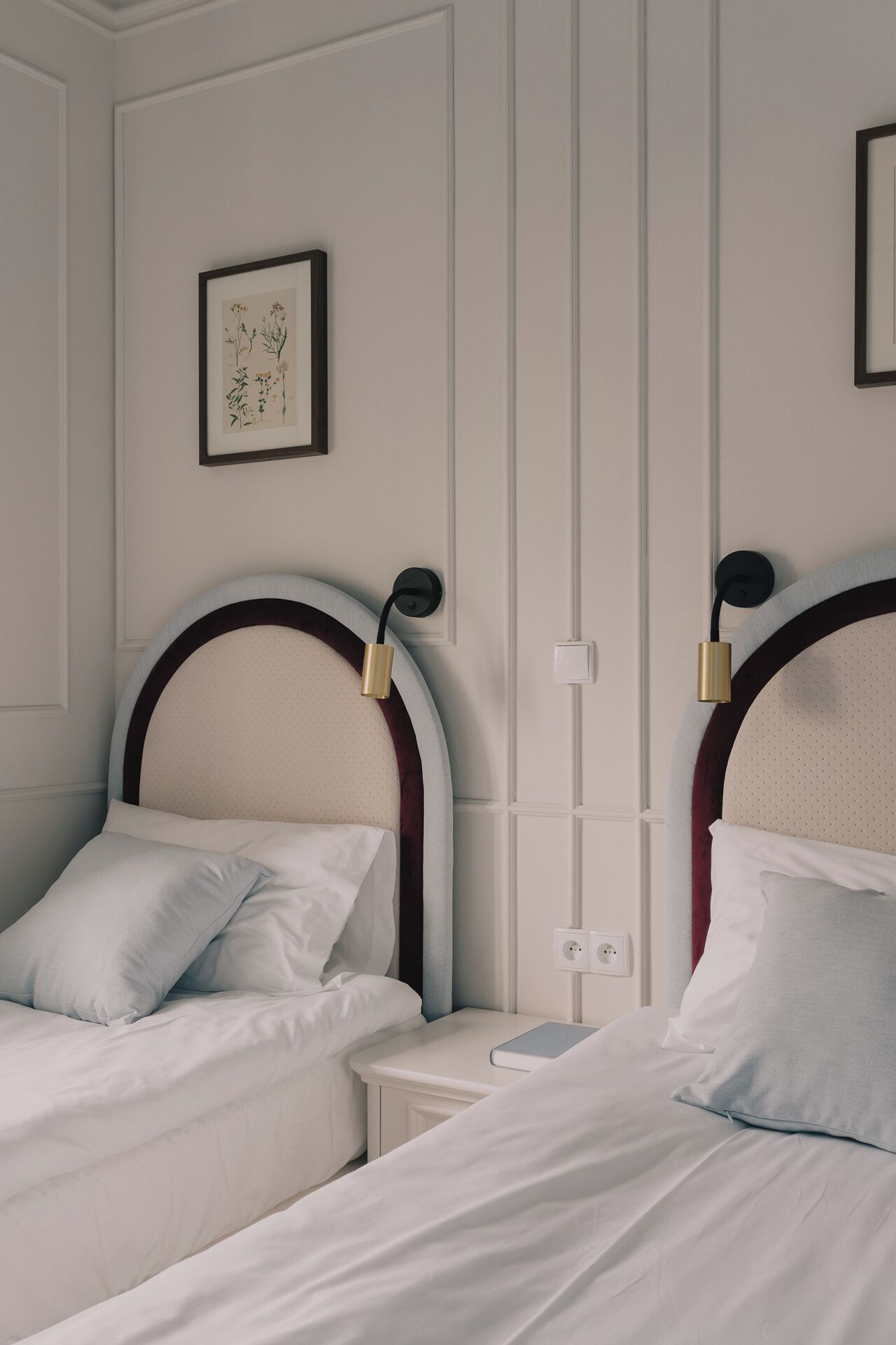 Une chambre d’hôtel avec deux lits, chacun doté d’une tête de lit et d’une lampe de chevet.