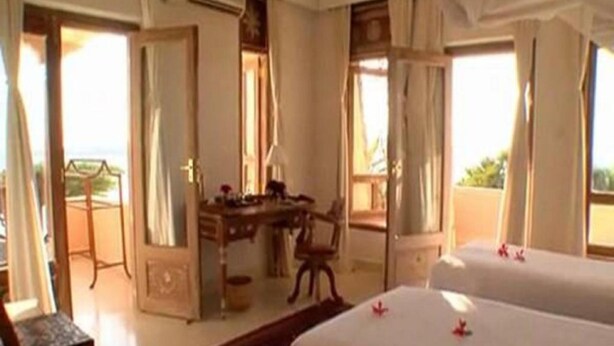 Habitación de hotel con dos camas, un escritorio y una silla.