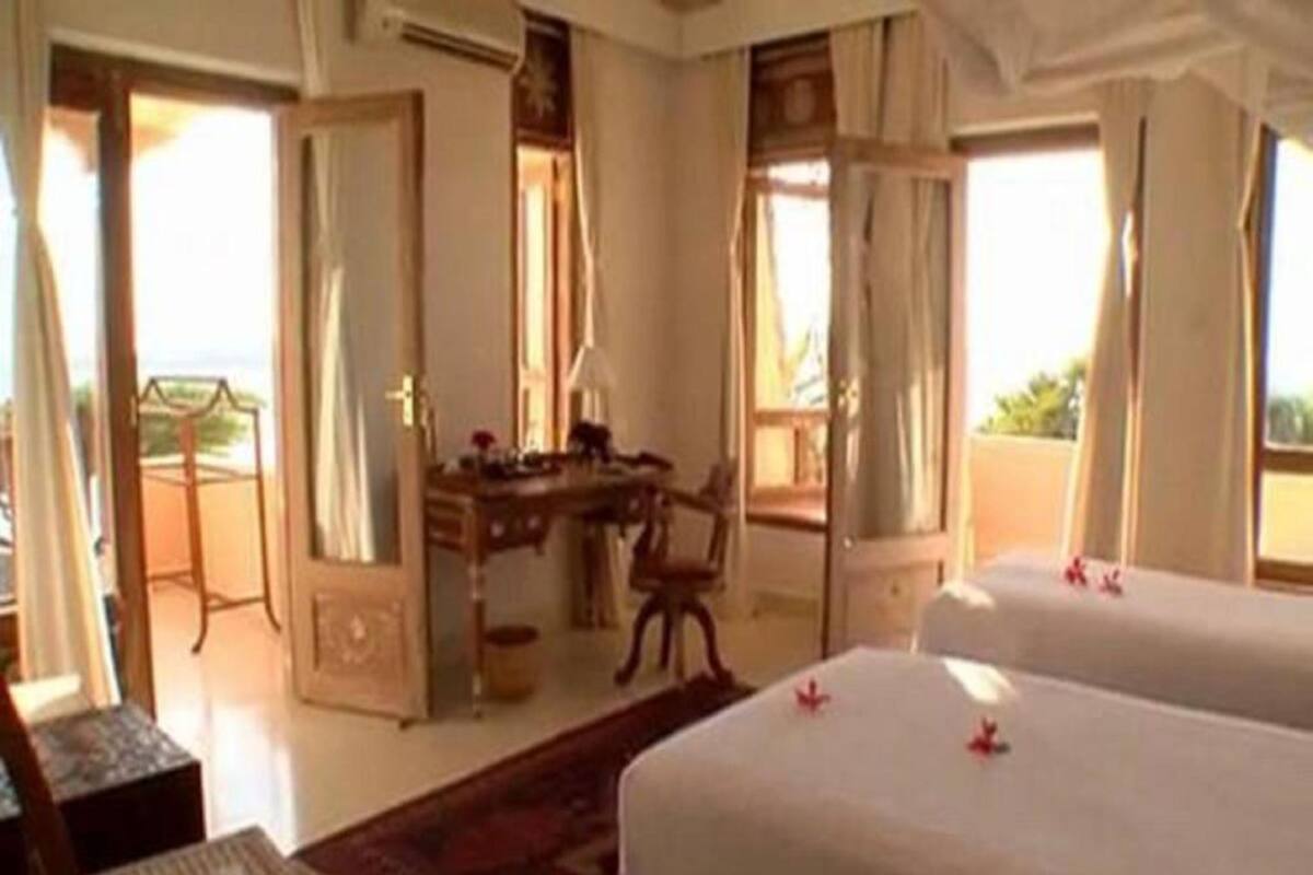 A hotel room with two beds, a desk, and a chair.