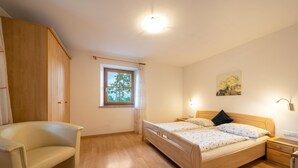 Ein Schlafzimmer mit Bett, Stuhl, Fenster und einem Gemälde an der Wand.
