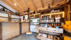 Ein rustikales Interieur mit Holzböden, die verschiedene Flaschen und Gläser zeigen, eine zentrale Theke mit einer Registrierkasse und einem gefliesten Boden.