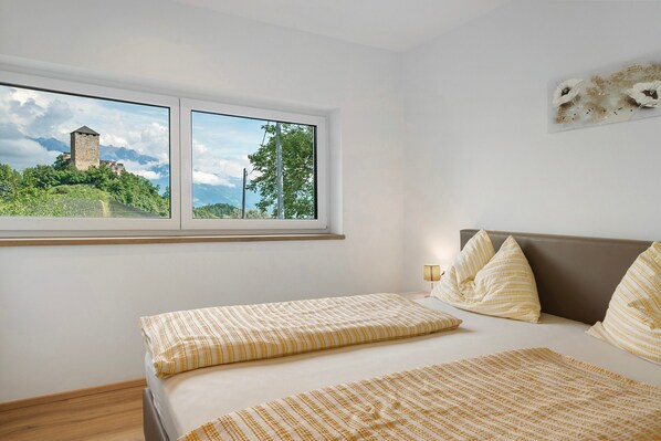 Quarto com uma janela grande, uma cama com roupa de cama listrada e uma obra de arte na parede.