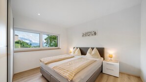 A bedroom with a large bed, a nightstand with a lamp, a window with a view of greenery, and a wall-mounted artwork. - Apartment 'Stettnerhof Mayenburg' with Mountain View, Terrace & Wi-Fi (Völlan/Lana)