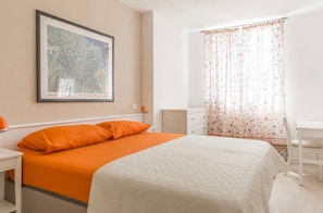 A bedroom with a bed, a nightstand, a dresser, a framed picture on the wall, and a window with floral curtains. - Apartment "Bilocale Colline di Bardolino 2" with Wi-Fi & Garden 023006-LOC-00151 (Bardolino)