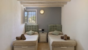 A room with two beds, a nightstand, a wall-mounted light, and a window with a view. - Country House That Welcomes Pets "Finca Can Paci" with Mountain Views (Santa Eulalia)