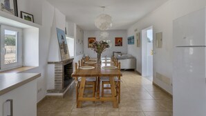 A modern kitchen with a dining table, chairs, a fireplace, and artwork on the walls. - Country House That Welcomes Pets "Finca Can Paci" with Mountain Views (Santa Eulalia)