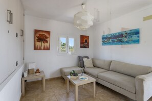 A living room with a sofa, a coffee table, a lamp, and artwork on the walls. - Country House That Welcomes Pets "Finca Can Paci" with Mountain Views (Santa Eulalia)