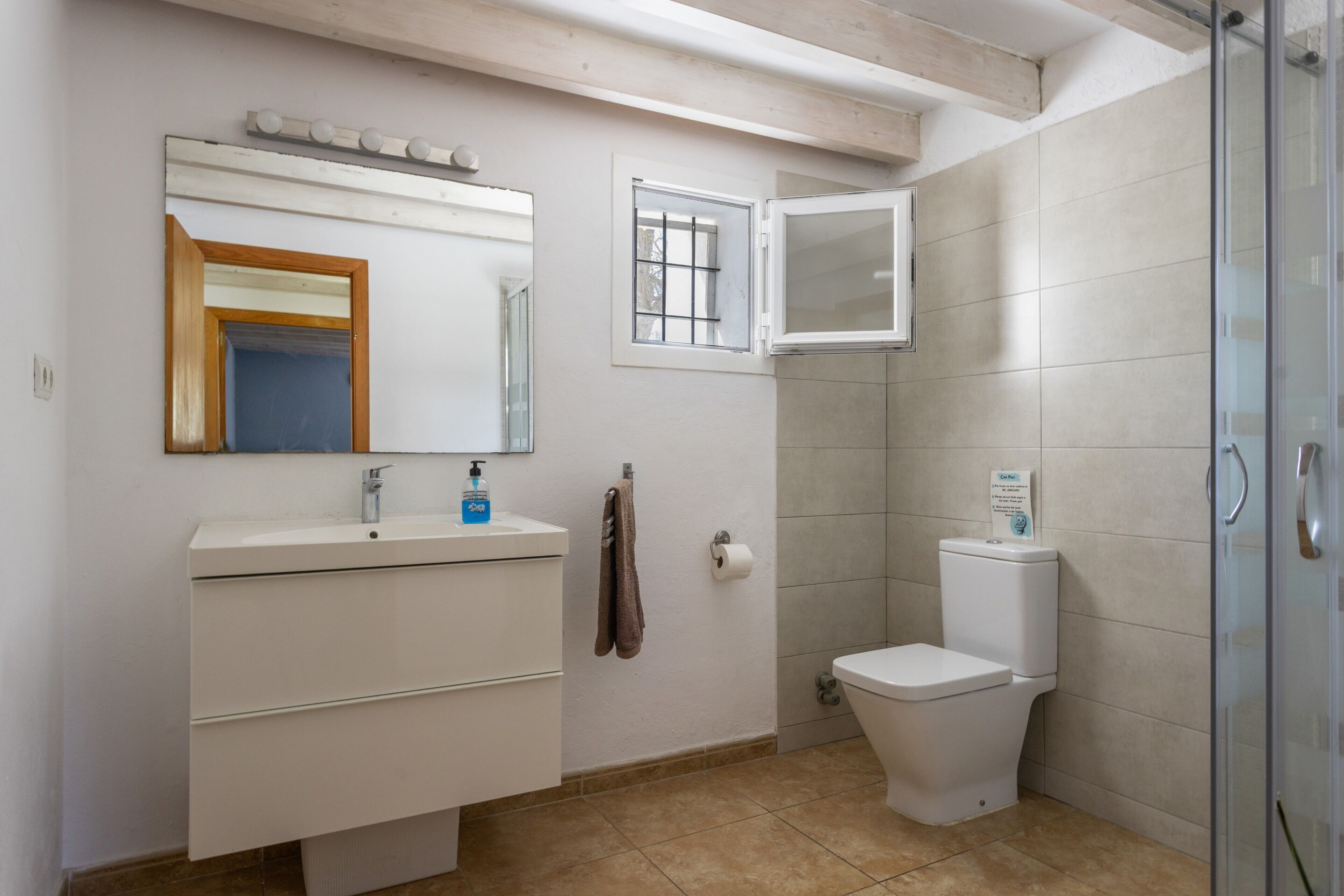 Un baño con lavamanos, espejo e inodoro blancos.