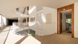 A modern interior with a spiral staircase, a wooden door, and a view into another room. - "Apartment Higueron Wave 1" with Sea View, Pool, Wi-Fi & Terrace (Fuengirola)