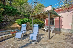 A patio with two lounge chairs, a table, and a covered area.