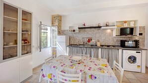 A compact kitchen with a dining area, a washing machine, and a microwave. - Holiday Home "Casetta Antonella" with Mountain View, Garden & Terrace (Fraz. Lecchiore comune Dolcedo)