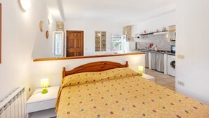 A bedroom with a bed, bedside tables, a nightstand, a wardrobe, and a view of a kitchen with a washing machine. - Holiday Home "Casetta Antonella" with Mountain View, Garden & Terrace (Fraz. Lecchiore comune Dolcedo)