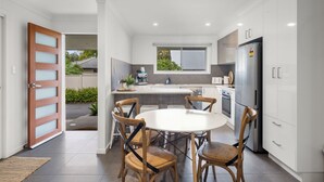 Una cocina moderna con armarios blancos, una isla central y una zona de comedor con mesa redonda y sillas.