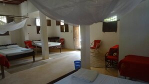A dormitory room with two beds, a chair, and a table. - Dudu Villas N Backpackers (Lamu)