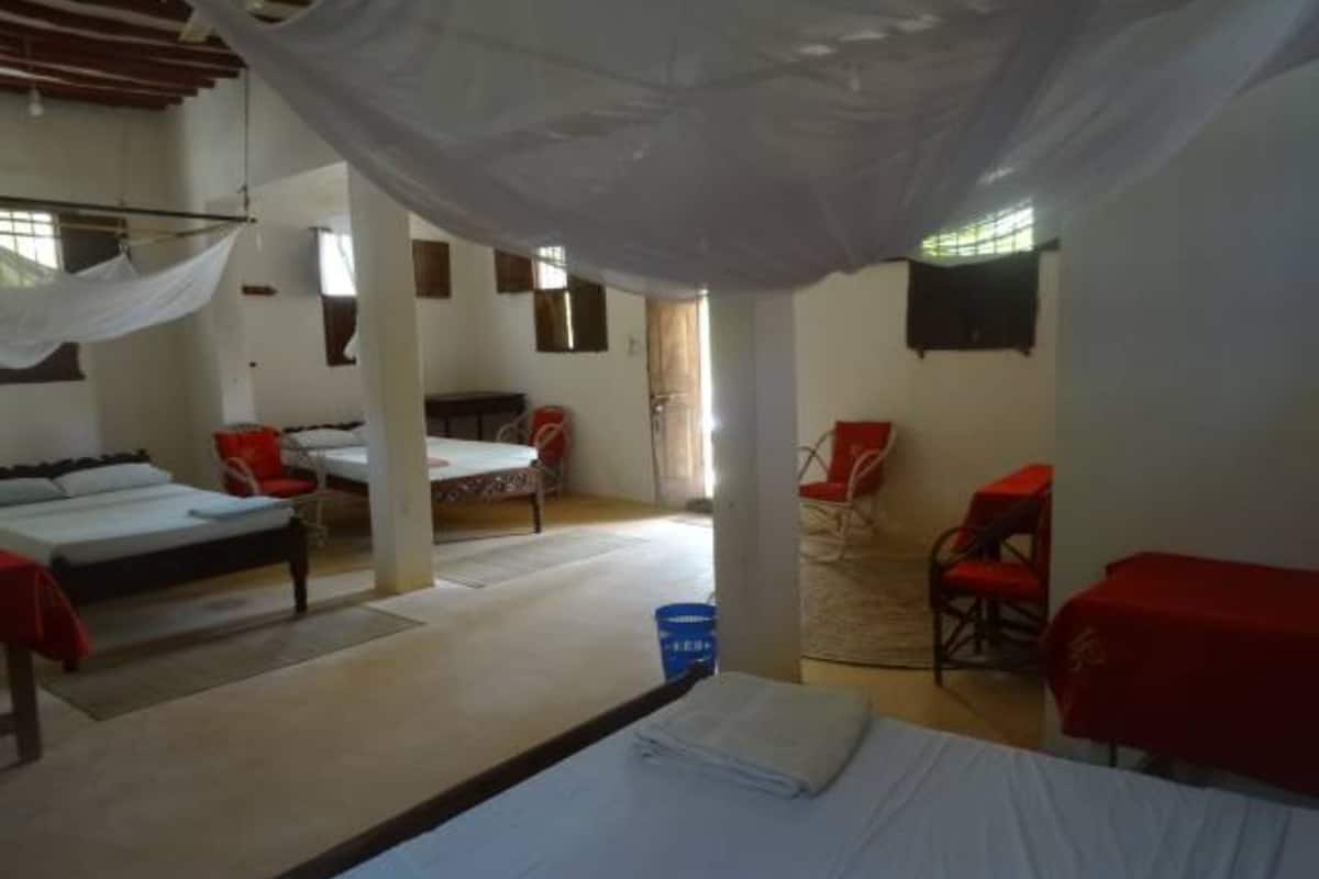 A dormitory room with two beds, a chair, and a table.