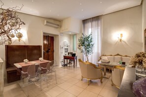 A modern living room with a dining area, a sofa, a coffee table, and a decorative plant. - Luxury apartment in the historical center. (Roma)