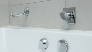 A modern bathroom with a white bathtub, chrome fixtures, and tiled walls.