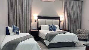 A hotel room with two beds, a nightstand, a chair, and an air conditioning unit. - Letsatsing Lodge (Rustenburg)