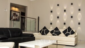 A modern living room with a black and white sofa, a white coffee table, and a glass railing in the background. - Letsatsing Lodge (Rustenburg)