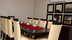 A dining area with a dark wooden table, beige upholstered chairs, and a red placemat.
