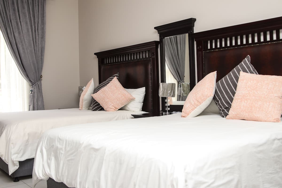 A hotel room with two beds, each with white bedding and multiple pillows.