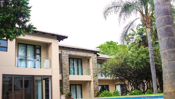 A two-story building with balconies, large windows, and a swimming pool. - Letsatsing Lodge (Rustenburg)