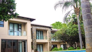 A two-story building with balconies, large windows, and a swimming pool. - Letsatsing Lodge (Rustenburg)