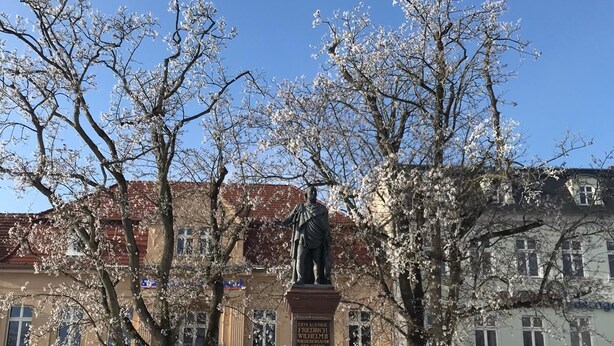 Eine Statue in einem Platz, bedeckt mit Schnee, umgeben von Gebäuden.