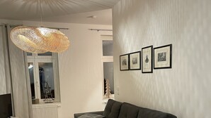 Ein modernes Wohnzimmer mit einem Ecksofa, einem Glastisch und einem gemusterten Teppich.
