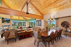 Une salle à manger spacieuse avec un haut plafond en bois, de grandes fenêtres et une cheminée.