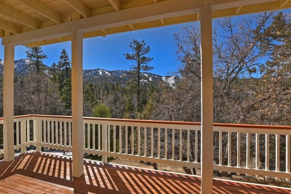 Une terrasse en bois, dotée de rampes blanches, qui offre une vue sur un paysage montagneux.
