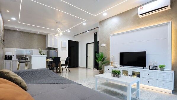 A modern living room with a sofa, a TV, a coffee machine, and a dining area with chairs and a table. - NOVO 8 Jonker Street Melaka By I Housing (Malacca City)