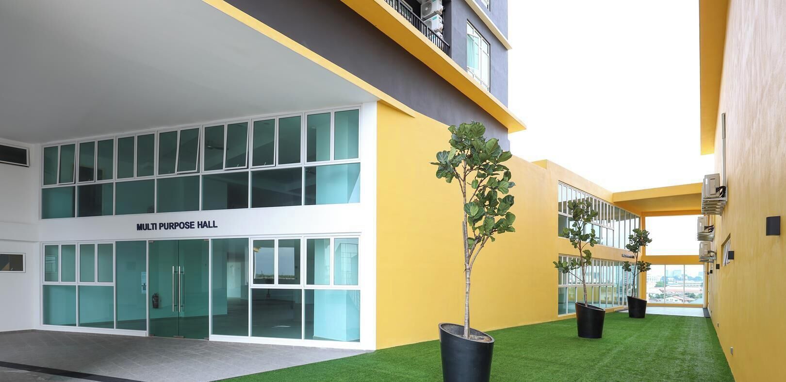 A multi-purpose hall with large windows and a yellow exterior wall.